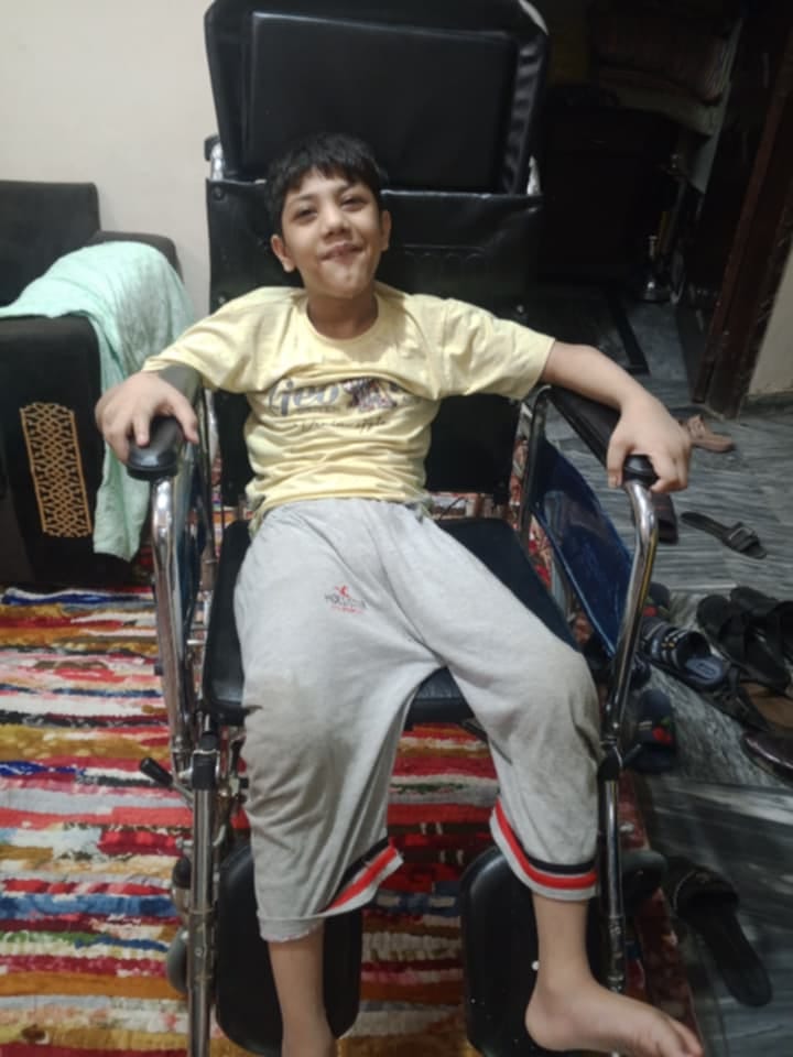 A boy smiling in his wheelchair at home.