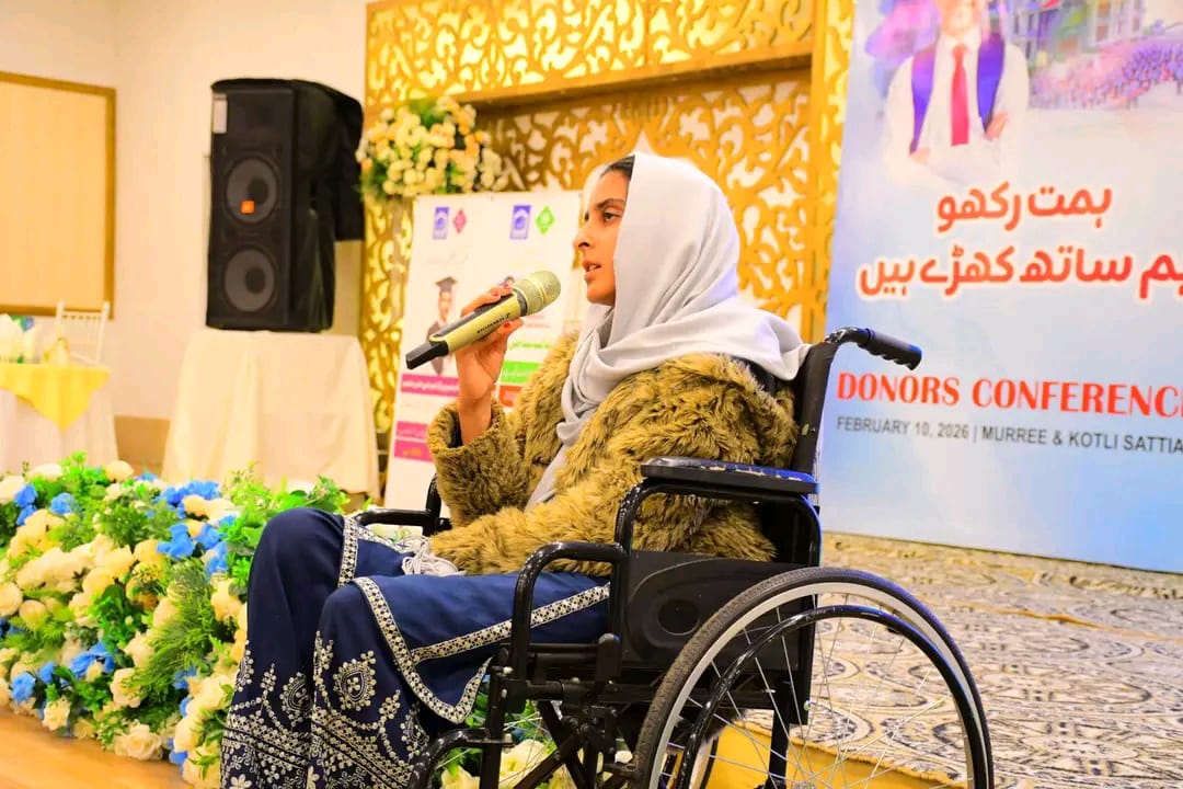 Momina Abbasi speaking into a microphone from her wheelchair at a conference.
