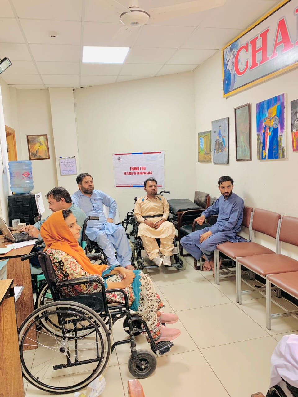 A group of wheelchair users and staff gathered together in a centre in Pakistan.